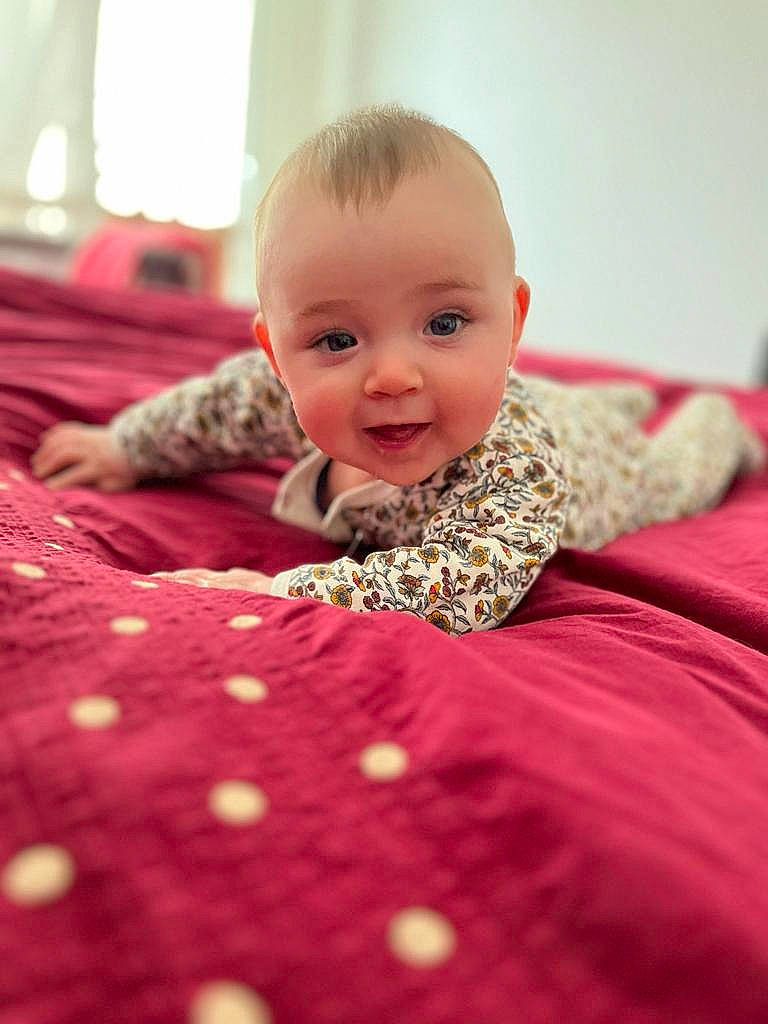 Anna a rejoint le concours — aidez-le/la à gagner de superbes lots ! baby, baby_toddler_clothing, bed, bedding, child, close_up, comfort, eye, flooring, happy, linens, magenta, person, petal, pink, skin, sleeve, smile, textile, toddler