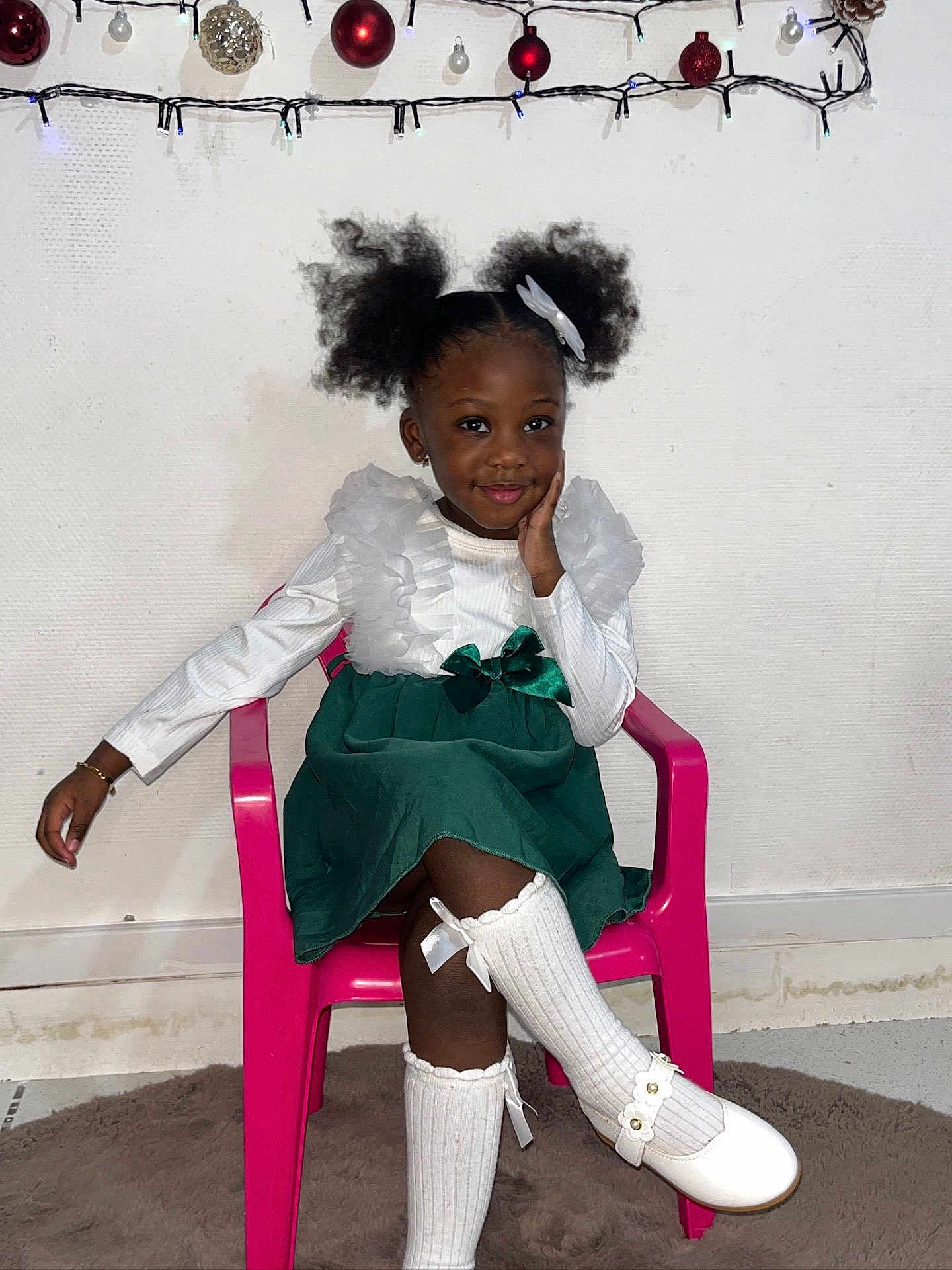 Alycia a rejoint le concours — aidez-le/la à gagner de superbes lots ! child, girl, smile, pigtails, dress, white_shirt, green_skirt, socks, white_shoes, pink_chair, indoor, holiday_decorations, string_lights, ornaments, wall, floor, carpet, pose, cute, portrait