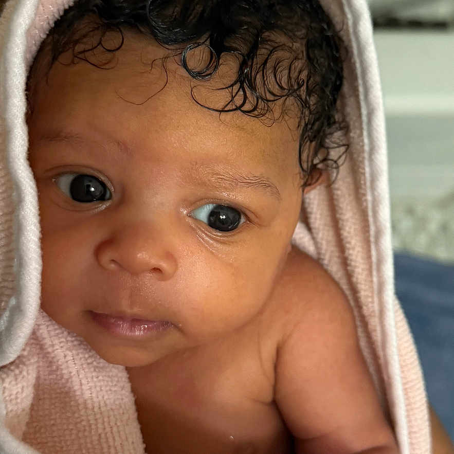 Nylah is registered to the contest to win money with this photo: adorable, baby, child, closeup, curly_hair, cute, expression, eyes, face, human, indoor, infant, newborn, person, pink, portrait, skin, soft_texture, towel, wrapped