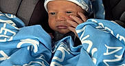 Alegend is registered to the contest to win money with this photo: newborn, baby, infant, car_seat, blanket, hat, blue, white, clothing, face, hand, wrapped, cozy, child, young, cute, portrait, indoors, person, seat