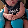 Enoch is registered to the contest to win money with this photo: baby, child, infant, portrait, sitting, helmet, hat, blue_seat, wide_eyed, surprised, face, hands, indoors, close_up, casual_clothing, dark_shirt, furniture, home, photography, adorable
