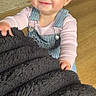 toddler, child, smiling, blanket, overalls, pink_shirt, floor, rug, indoor, person, cute, happy, baby, portrait, clothing, head, hand, earrings, standing, playful