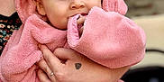 Rafaël a rejoint le concours — aidez-le/la à gagner de superbes lots ! baby, child, closeup, cute, eyes, face, fluffy, hand, holding, indoor, nibble, person, pink_towel, portrait, ring, skin, sleeve, soft_texture, tattoo, wrapped