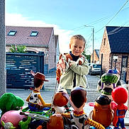Maël a rejoint le concours — aidez-le/la à gagner de superbes lots ! child, boy, toys, woody, buzz_lightyear, mr_potato_head, spiderman, yoda, hulk, rex_dinosaur, imaginative_play, outdoor, backpack, daylight, suburban, sky, fence, brick_house, window, street
