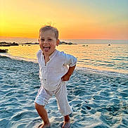 Maël a rejoint le concours — aidez-le/la à gagner de superbes lots ! child, beach, sand, sunset, sea, water, sky, barefoot, smiling, playful, running, light_clothing, outdoor, nature, vacation, sunlight, horizon, shore, fun, happy