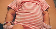 Nova is registered to the contest to win money with this photo: baby, newborn, sleeping, infant, pink_onesie, headband, bow, mittens, legs, feet, adult_legs, skin, cute, peaceful, resting, portrait, indoors, human, closeup, soft_lighting