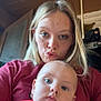 woman, baby, indoor, selfie, pout, face, blonde_hair, blue_eyes, casual_clothing, cartoon_shirt, red_shirt, door, pipe, expression, portrait, person, child, skin, head, closeup