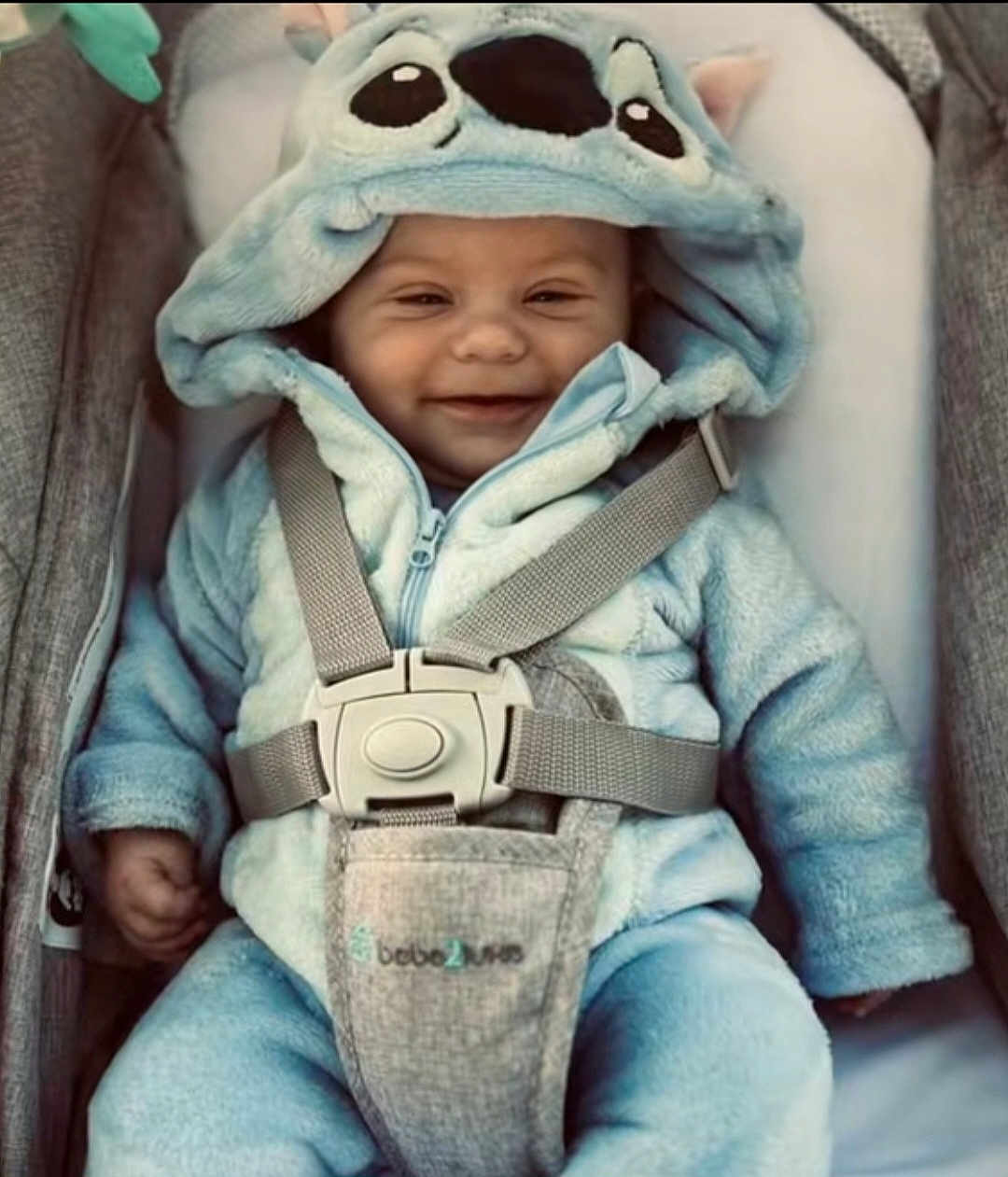 William Dedinger participe au concours pour gagner de l'argent avec cette photo : baby, infant, smiling, blue_onesie, hood, car_seat, safety_harness, cute, plush_clothing, child, happy, portrait, young_child, indoors, seatbelt, comfort, warm_clothing, baby_clothing, baby_face, small_child