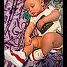 baby, infant, child, onesie, sneakers, pacifier, blanket, purple, pattern, clothing, footwear, cute, chubby, skin, person, indoor, laying_down, hand, leg, head