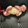 Jose Luis is registered to the contest to win money with this photo: baby, infant, onesie, yellow_clothing, bear_print, baby_fingers, curious_eyes, black_leather, couch, sofa, indoor, child, cute, relaxed, skin, human, portrait, sitting, baby_leg, baby_foot