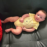 Jose Luis is registered to the contest to win money with this photo: baby, child, infant, yellow_onesie, smile, face, couch, leather, relaxing, cute, happy, plump, skin, head, arm, leg, foot, indoors, portrait, person