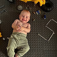 Yaroslav participe au concours pour gagner de l'argent avec cette photo : baby, child, smile, toy, yellow_toy, tools, wrenches, screwdriver, allen_keys, floor_mat, clothing, pants, bare_chest, foot, hand, face, playtime, indoor, happy, infant