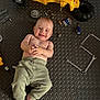 baby, child, smile, toy, yellow_toy, tools, wrenches, screwdriver, allen_keys, floor_mat, clothing, pants, bare_chest, foot, hand, face, playtime, indoor, happy, infant