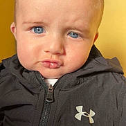 Ayden participe au concours pour gagner de l'argent avec cette photo : baby, baby_face, black_jacket, blue_eyes, child, close_up, clothing, cute, expression, face, head, indoors, person, portrait, pout, skin, under_armour, yellow_background, young_child, zipper