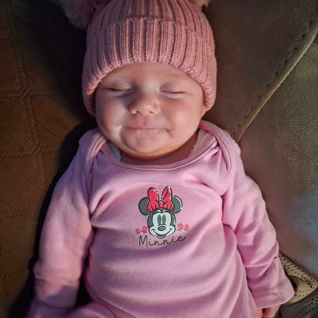 Esme-Rian joined the competition — help win amazing prizes! adorable, baby, child, closed_eyes, comfort, couch, cozy, cute, hat, indoors, infant, person, pink_clothing, pom_pom, resting, sleepy, small, smile, soft_furniture, warm