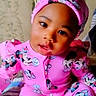 E'Mani is registered to the contest to win money with this photo: baby, child, pink_outfit, minnie_mouse, head_wrap, sitting, blanket, floral_background, cute, portrait, indoor, smiling, young_child, face, clothing, person, infant, fashion, comfort, relaxed
