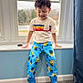 Ignacio is registered to the contest to win money with this photo: child, indoor, window, pajamas, minions, slippers, sonic, smiling, happy, toddler, carpet, blue_wall, white_window_frame, toy, curtain, short_sleeve_shirt, colorful_clothing, hair, person, standing
