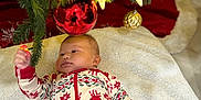 Keyri is registered to the contest to win money with this photo: baby, infant, christmas_tree, ornament, holiday, pajamas, reindeer_pattern, blanket, hand, decorations, festive, red, green, white, lights, celebration, indoors, cute, child, seasonal