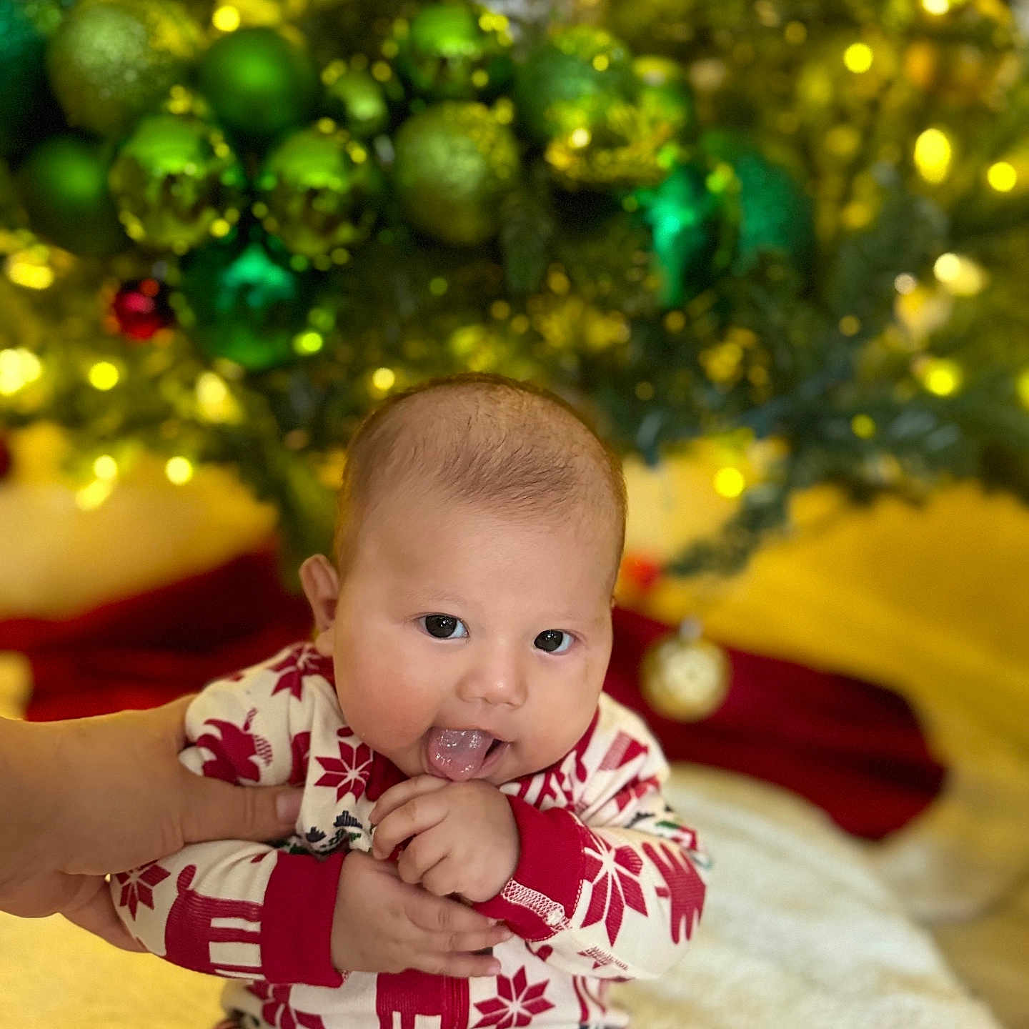 Keyri joined the competition — help win amazing prizes! baby, blurred_background, child, christmas_ornaments, christmas_tree, cute, decorations, festive_clothing, gold_ornaments, green_ornaments, hand_holding, holiday, holiday_season, indoor, infant, pajamas, portrait, red_and_white, smiling, tongue_out