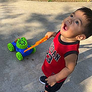 James joined the competition — help win amazing prizes! toddler, child, toy, mower, sidewalk, grass, red_jersey, shoes, outdoor, sunlight, curious, playing, summer, portrait, expression, young_child, casual_clothing, daytime, happy, person