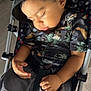 toddler, child, sleeping, hat, bucket_hat, stroller, polka_dot, patterned_shirt, black_clothing, gray_pants, hand, closed_eyes, indoors, footwear, nike_shoes, seat_belt, mickey_mouse_pattern, relaxed, cute, portrait