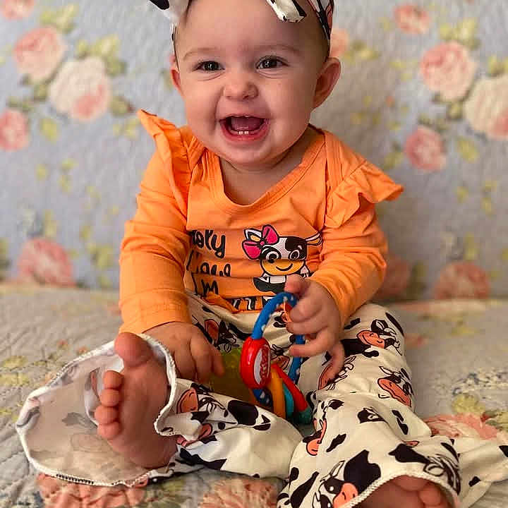 Presley is registered to the contest to win money with this photo: accessories, baby, babylaughing, couch, face, furniture, happy, head, headband, laughing, person, photography, portrait, quilt, sitting, smile