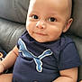 baby, infant, smiling, onesie, blue_clothing, puma_logo, couch, leather_furniture, indoor, cute, child, portrait, sitting, chubby_cheeks, short_hair, skin, hand, arm, face, happy