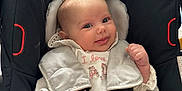 Thea-Rose is registered to the contest to win money with this photo: baby, car_seat, infant, smile, straps, white_clothing, padded_seat, toy, black, gray, happy, face, child, indoors, seatbelt, cute, young_child, head, small_hands, playful