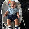 baby, smiling, baby_rocker, blue_shirt, navy_shorts, socks, indoor, child, happy, infant, seat, fabric, toy_pattern, cute, person, clothing, footwear, sitting, face, portrait
