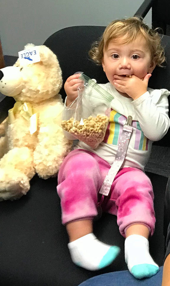 Remington is registered to the contest to win money with this photo: baby, baby_products, baby_toddler_clothing, cheek, child, companion_dog, fun, fur, happy, head, lap, magenta, person, pink, plush, sitting, sock, stuffed_toy, teddy_bear, toddler