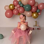 Evelyn is registered to the contest to win money with this photo: baby, balloon, birthday, child, chair, celebration, dress, flower_headband, first_birthday, girl, pink, tulle, smile, party, decorations, indoor, happy, number_one, floor, photography