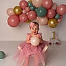baby, balloon, birthday, child, chair, celebration, dress, flower_headband, first_birthday, girl, pink, tulle, smile, party, decorations, indoor, happy, number_one, floor, photography