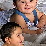 Noah joined the competition — help win amazing prizes! baby, smiling, infant, blue_suspender, bracelet, blanket, bed, cute, child, happy, portrait, indoors, soft_texture, skin, face, person, clothing, lying_down, baby_boy, close_up