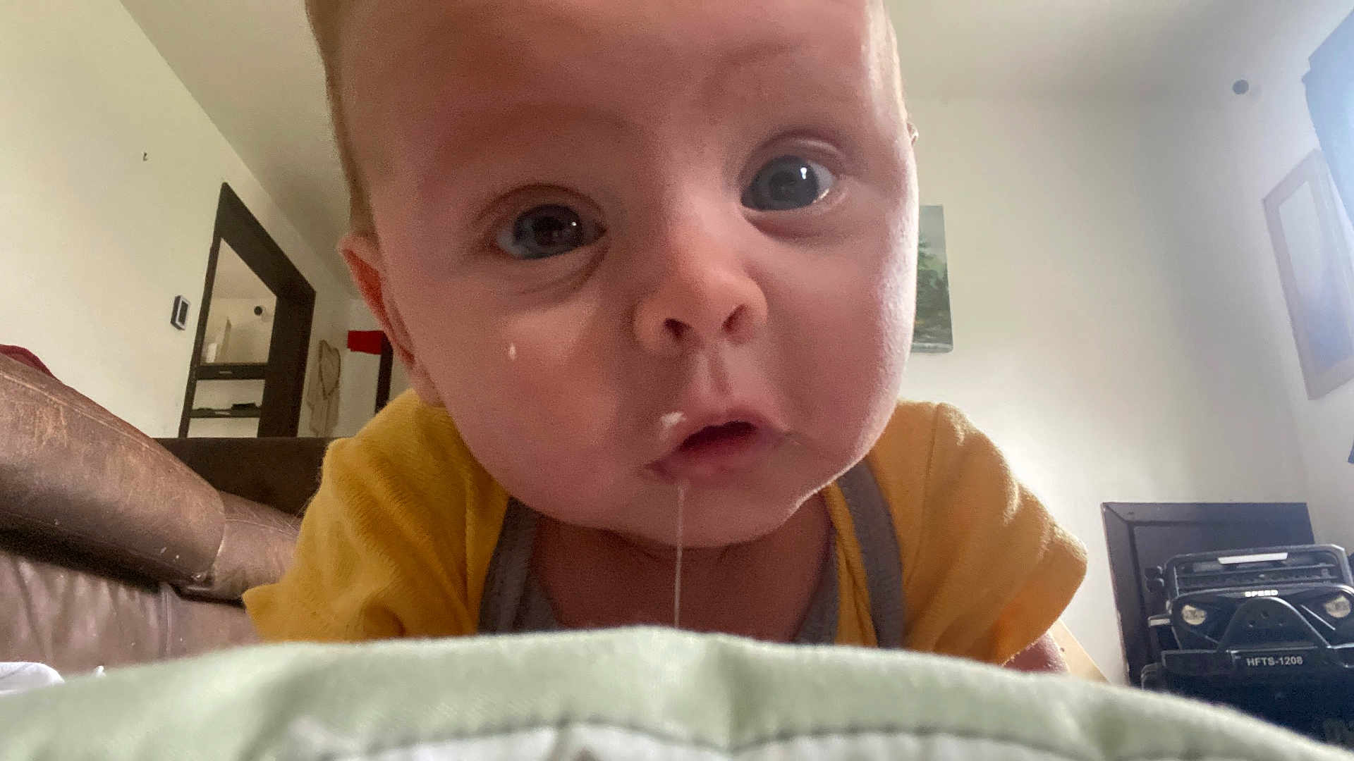 Dallas Reed Wegford is registered to the contest to win money with this photo: baby, drool, face, indoor, child, curious, closeup, yellow_clothing, living_room, couch, toy, soft_surface, person, head, expression, infant, home, skin, wide_eyes, mouth