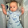 Dallas Reed Wegford is registered to the contest to win money with this photo: baby, crib, onesie, whale_pattern, infant, blue_clothing, pillow, mesh_sides, baby_bed, raised_arms, cute, portrait, indoors, child, newborn, sleep_area, baby_garment, soft_fabric, resting, curious_expression