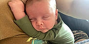 Dallas Reed Wegford is registered to the contest to win money with this photo: baby, sleeping, child, infant, green_clothing, cuddling, arm, person, closeup, peaceful, resting, human, skin, cute, newborn, portrait, indoor, soft_light, comfort, toddler