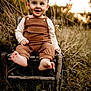 toddler, child, smiling, barefoot, overalls, long_sleeve_shirt, wooden_chair, outdoor, grass, nature, sunset, golden_hour, portrait, happy, young_child, rustic, field, cute, sitting, innocence