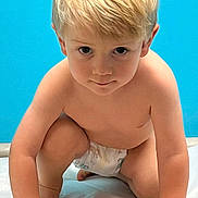 Kameron is registered to the contest to win money with this photo: toddler, child, blonde_hair, diaper, crouching, blue_background, indoor, curious, bare_chest, young_child, portrait, hands, knees, skin, expression, baby, floor, light, person, cute