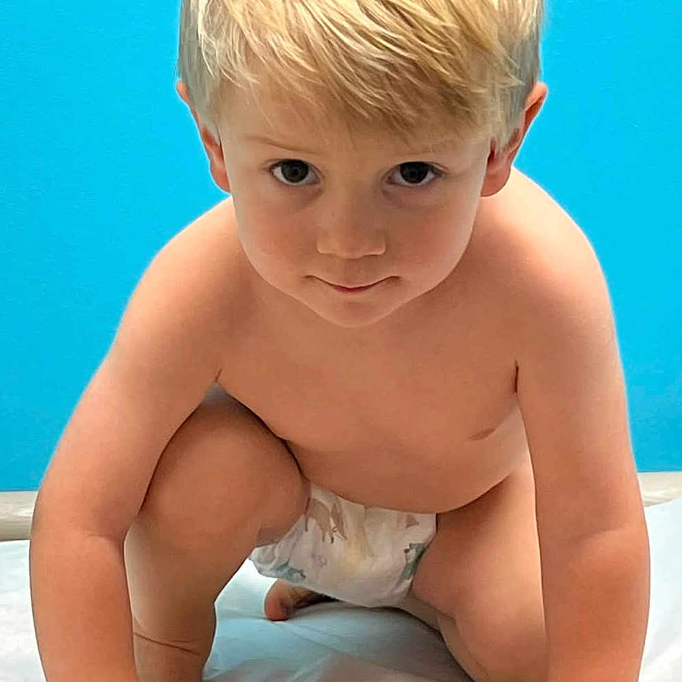 Kameron is registered to the contest to win money with this photo: toddler, child, blonde_hair, diaper, crouching, blue_background, indoor, curious, bare_chest, young_child, portrait, hands, knees, skin, expression, baby, floor, light, person, cute