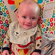 Silas joined the competition — help win amazing prizes! baby, infant, smiling, child, bib, onesie, blanket, colorful, baby_seat, patterned, animal_print, face, happy, cute, indoor, portrait, clothing, comfort, toddler, young_child
