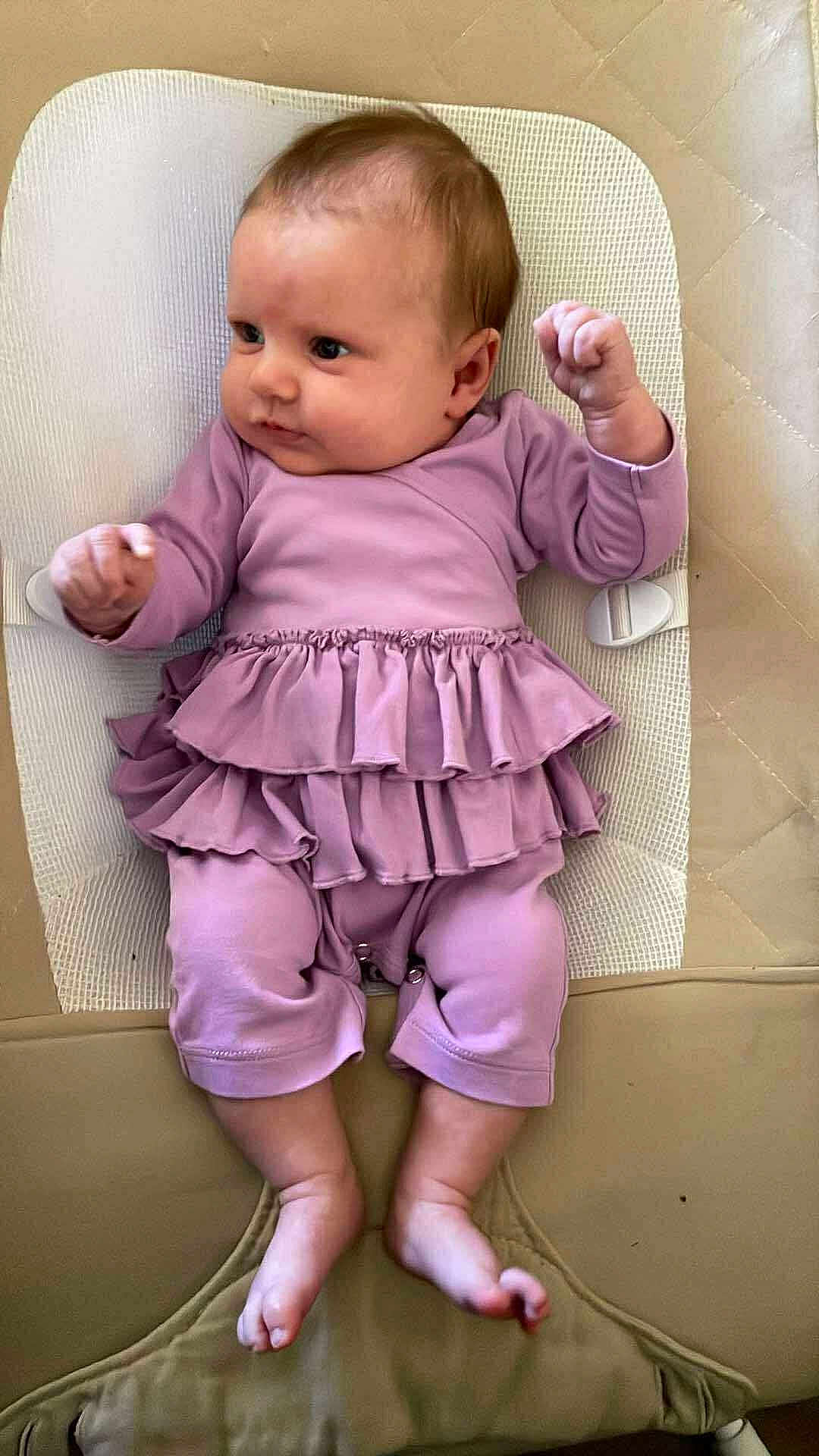 Elisa is registered to the contest to win money with this photo: baby, infant, child, purple_clothing, ruffles, cushion, lying_down, barefoot, cute, skin, face, hands, legs, feet, indoors, soft_fabric, closeup, newborn, expression, small_fingers