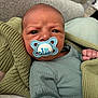 Bode joined the competition — help win amazing prizes! baby, pacifier, infant, blanket, knitwear, green_clothing, face, portrait, indoors, couch, expression, newborn, cute, child, hand, sleeve, soft_texture, comfort, resting, closeup