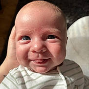 Bode is registered to the contest to win money with this photo: baby, smiling, tongue_out, blue_eyes, striped_clothing, onesie, giraffe_print, hand, closeup, face, infant, cute, happy, portrait, skin, head, cheeks, indoors, soft_light, expression