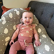Leah joined the competition — help win amazing prizes! baby, child, smile, happy, infant, cushion, cloud_pattern, pink_clothing, sitting, indoor, sofa, cute, joyful, person, face, home, comfort, plush, cozy, casual