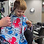 barbershop, boy, cape, chair, child, clothing, comb, cute, haircut, haircutting, hairdresser, hairstyle, happy, indoor, kid, person, scissors, short_hair, sitting, smile
