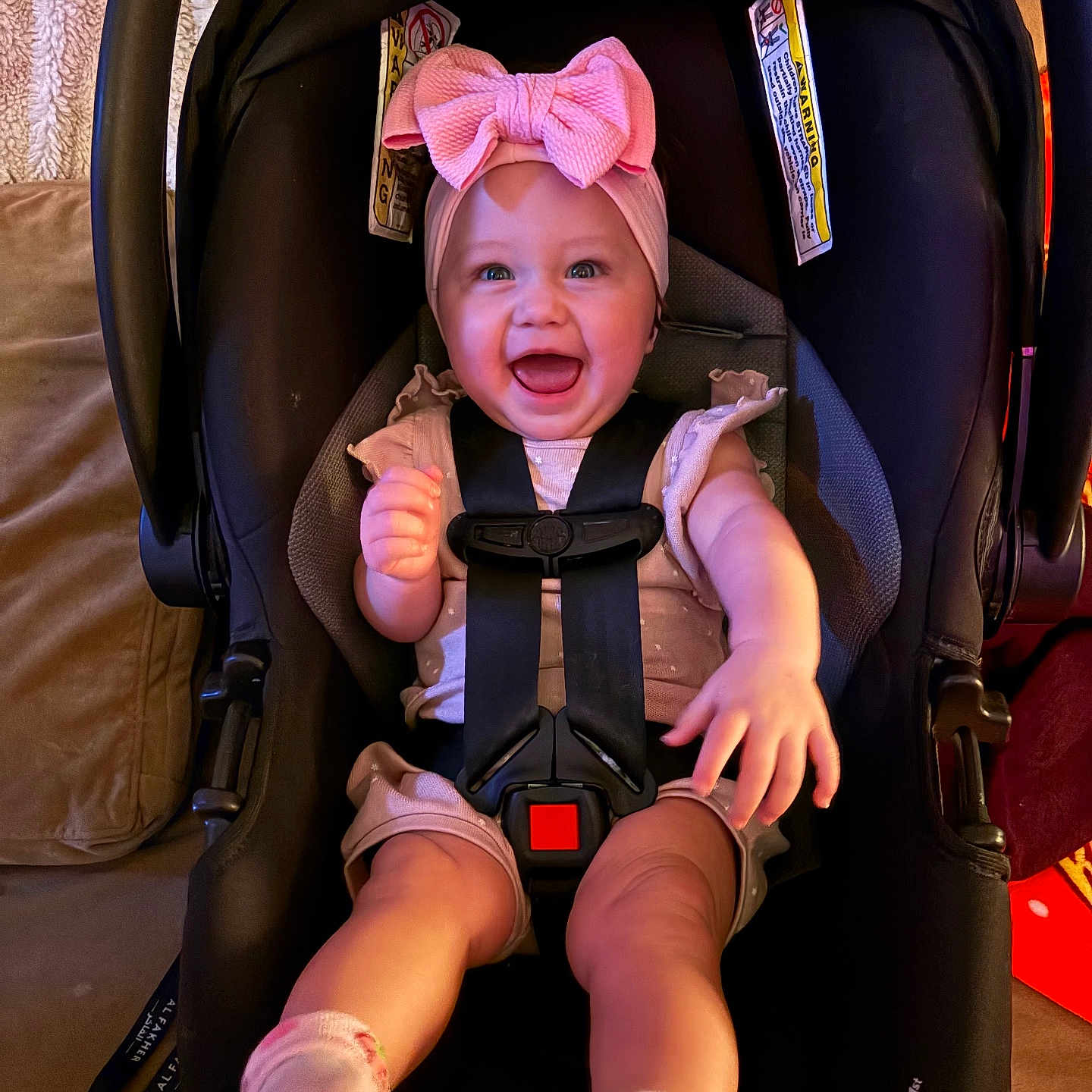Lucelia is registered to the contest to win money with this photo: accessory, adorable, baby, bow, car_seat, child, cozy, face, happy, harness, headband, indoor, infant, laughing, legs, pink, portrait, seat, smile, socks