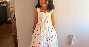 Eliana joined the competition — help win amazing prizes! child, curly_hair, floral_pattern, footwear, furniture, girl, happy, home_interior, indoor, lamp, light_switch, picture_frame, portrait, shoes, smiling, socks, standing, tile_floor, wall, white_dress