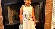 Eliana is registered to the contest to win money with this photo: child, curly_hair, cute, dress, fashion, fireplace, floral_pattern, girl, happy, home, indoor, pink_bow, portrait, shoes, smile, socks, standing, tile_floor, white_dress, young_child