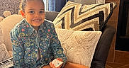 Eliana joined the competition — help win amazing prizes! balloons, black_shoes, child, couch, curtain, denim_jacket, fireplace, girl, hair_bun, keyboard, legs, living_room, patterned_jacket, pink_bow, pink_socks, plush_toy, sitting, smiling, throw_pillow, toy