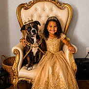 Eliana is registered to the contest to win money with this photo: basket, child, costume, crown, curly_hair, decor, dog, dress, floor, furniture, golden, happy, indoor, luxury, pet, portrait, princess, royalty, smile, throne